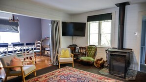 A living room with a fireplace, a television, and a dining area with chairs and a table. - Spacious 4-Bed Home in Central Tenterfield (Tenterfield)