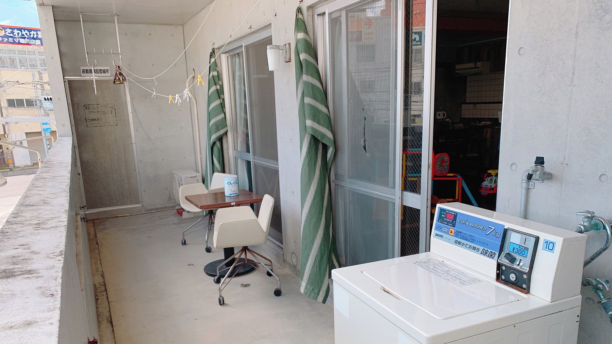 A small room with a washing machine, a table, chairs, and a window with curtains.