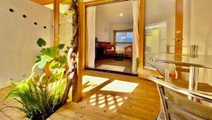 Une pièce moderne avec un plafond en bois, une table en verre et une vue sur l’espace de vie, grâce à une porte ouverte.