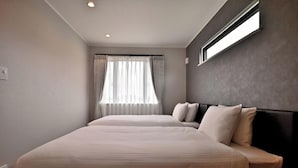 Hotellihuone, jossa on suuri sänky, ikkuna, jossa on verhot, ja seinälle asennettu valaisin.