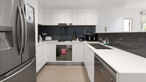 Een moderne keuken met roestvrijstalen apparatuur, witte kasten en een inbouwoven.