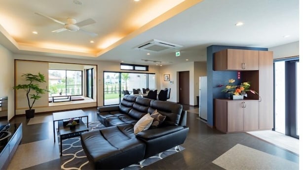 A modern hotel lobby with a black leather sofa, a coffee table, and a potted plant. - Sumuide Terrace H (Nago)