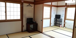 Una habitació japonesa tradicional amb paviment de tatami, una televisió sobre un moble i una porta corredissa.