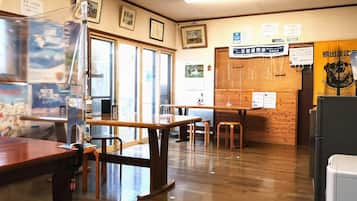 A restaurant interior with wooden tables and chairs, a counter, and various signs and notices on the walls.