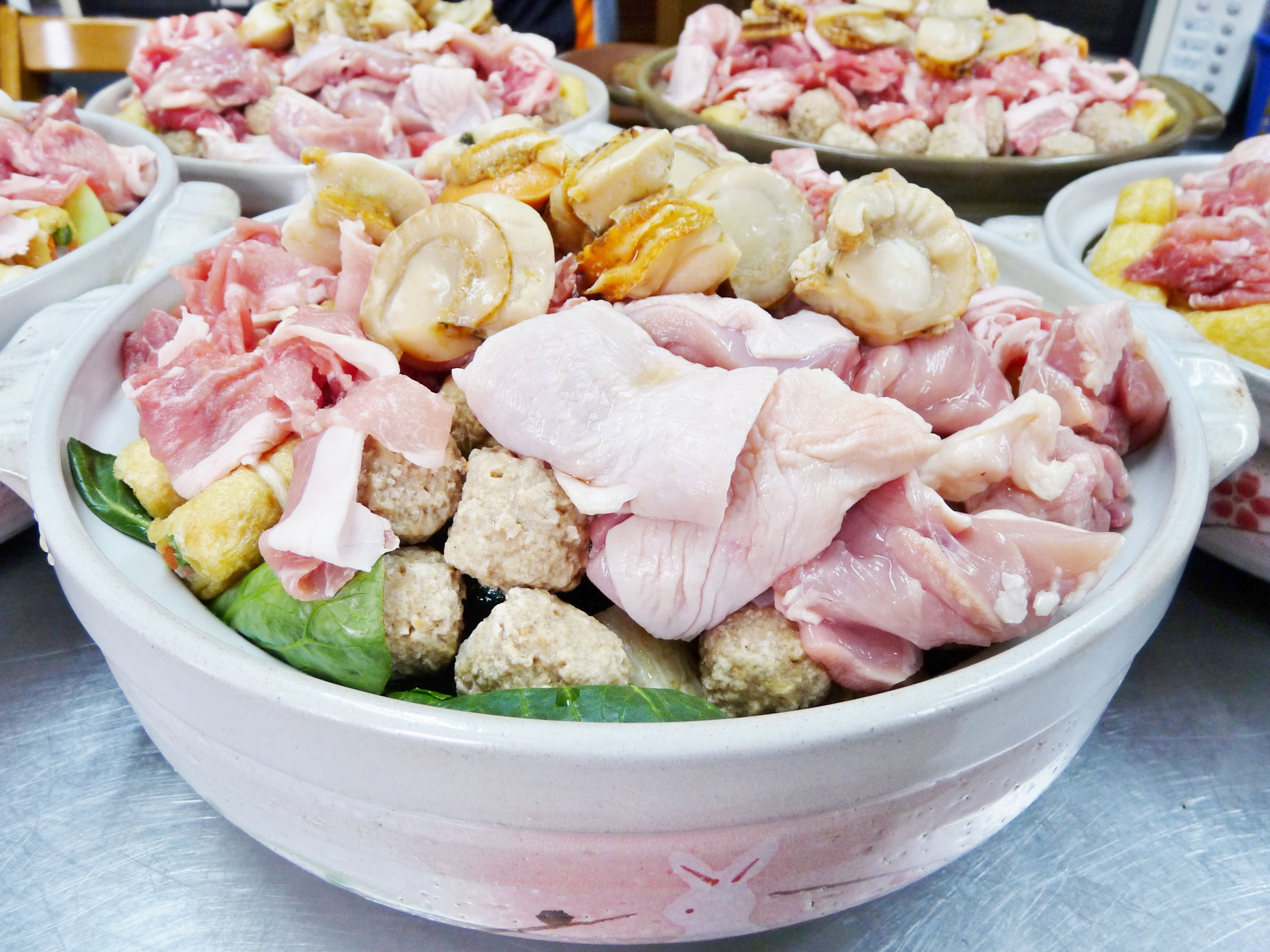 A bowl of assorted raw meats and vegetables.