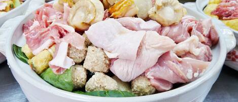 A bowl of assorted raw meats and vegetables.