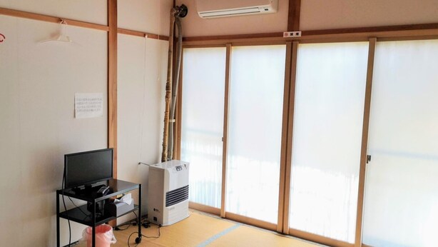 A room with tatami flooring, a television on a low table, a heater, and sliding shoji doors.