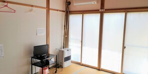 Habitació amb combinat de tatami, televisió sobre un suport negre, aire condicionat i portes corredisses shoji.