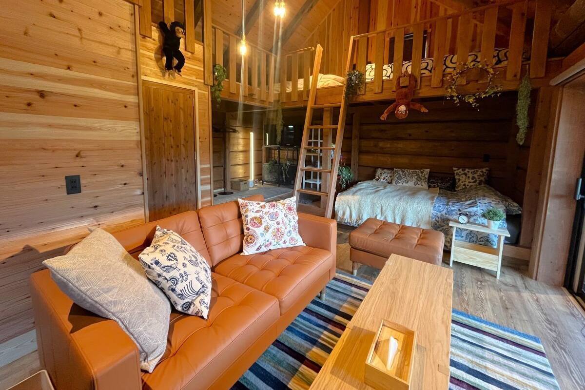Un interior acogedor de cabaña con un sofá, una mesa de madera, una escalera y una cama litera.