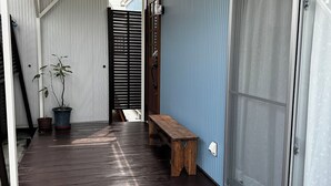 A narrow wooden corridor with a bench and potted plants. - Tabijiman (Nago)