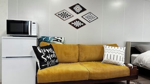 A modern living room with a sofa, a microwave, and a refrigerator. - Tabijiman (Nago)