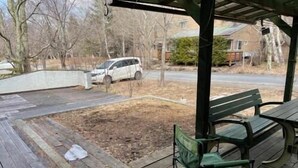 A covered outdoor area with a wooden deck, a green bench, and a table. - Pension Xaymaca (Hara)