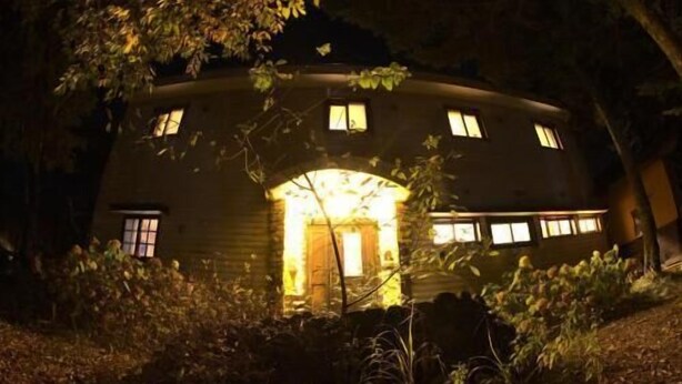 A circular building with a central entrance and multiple windows, surrounded by foliage. - Pension Xaymaca (Hara)