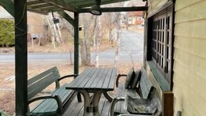 An outdoor patio with wooden tables and chairs, a grill, and a sink. - Pension Xaymaca (Hara)