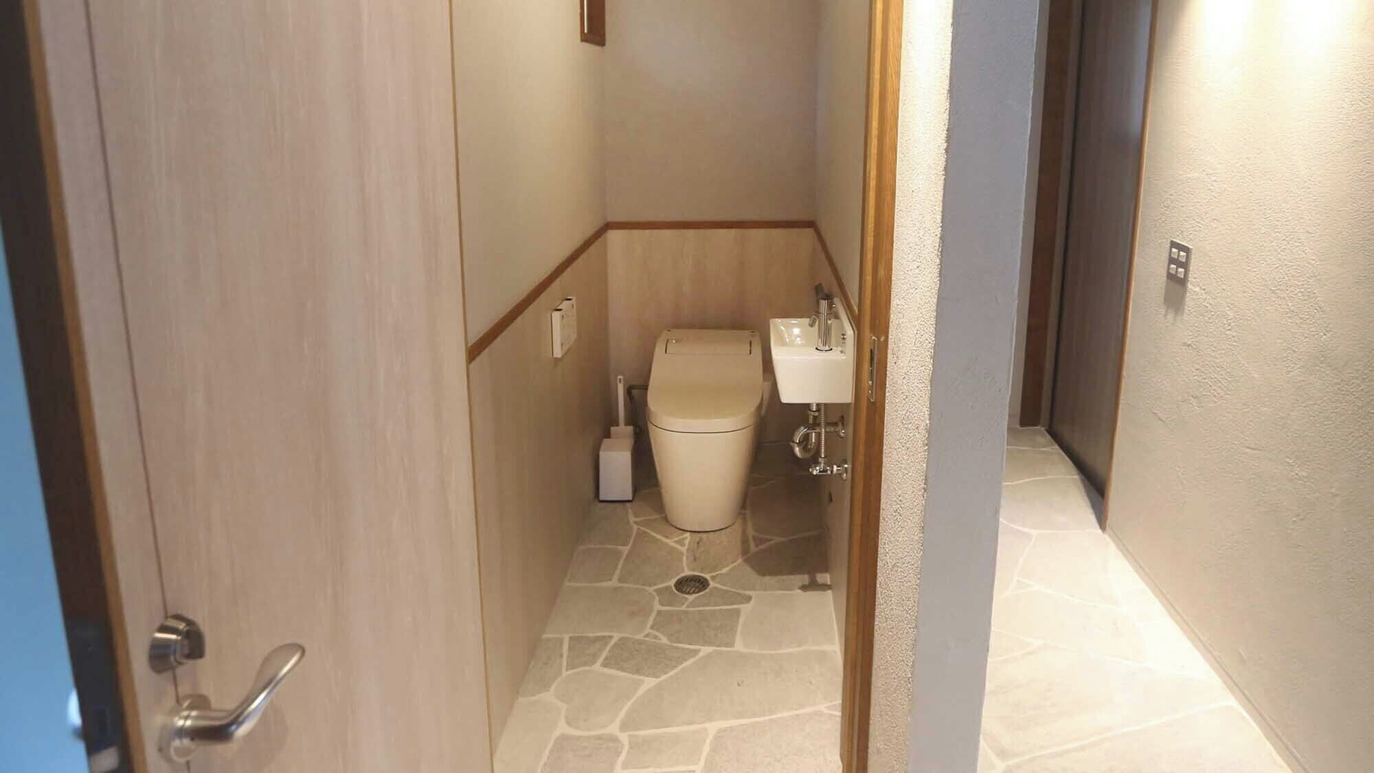 A narrow hallway leading to a small bathroom with a toilet, a sink, and a shower area.