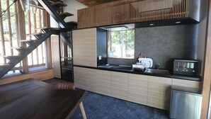 A modern kitchen with a built-in stove, a sink, and a window overlooking a forest. - Okutass Resort Villa Terra (Awaji)