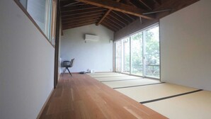 A room with tatami flooring, a sliding glass door leading to a balcony, and a chair in the corner. - Okutass Resort Villa Terra (Awaji)