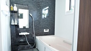 Une salle de bain moderne équipée d’une baignoire, d’une douche, d’un lavabo et d’un miroir.