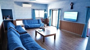 Un salon avec un canapé bleu, une table basse en bois et un téléviseur fixé au mur.