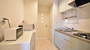 A modern kitchen with white cabinets, a microwave, a sink, and a stove. - Pinehills Hotel <miyakojima> (Miyakojima)
