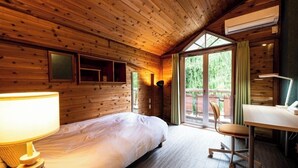 Una habitación de cabaña de madera con cama, escritorio, silla y equipo de aire acondicionado.