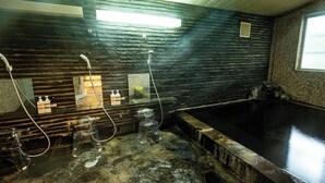 Un baño de paredes de piedra con una bañera grande, zona de ducha y un espejo.