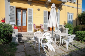A patio with outdoor furniture, a table, chairs, and a large umbrella. - casa di alfredo (Siena)