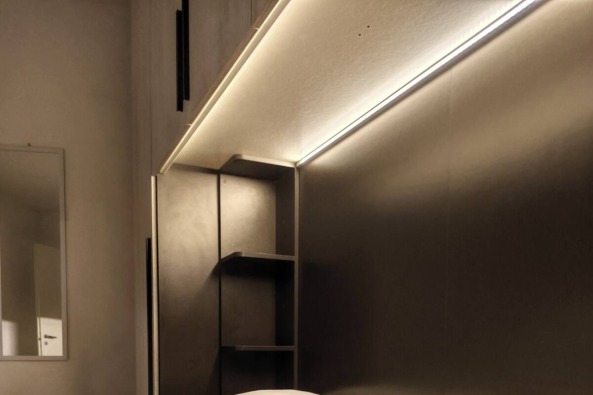 A modern bedroom with a bed, a nightstand, and a built-in shelf.