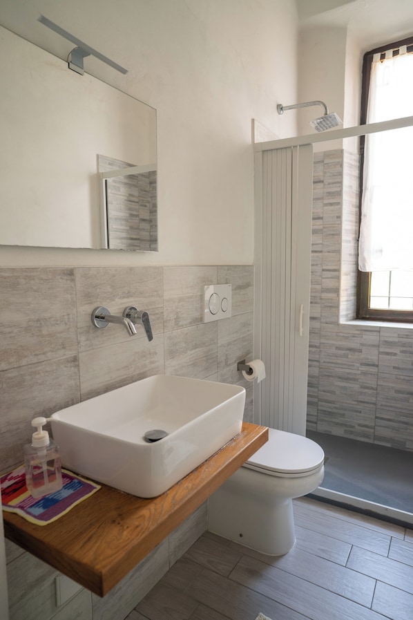 A modern bathroom with a white sink, a toilet, and a shower. - casa di alfredo (Siena)