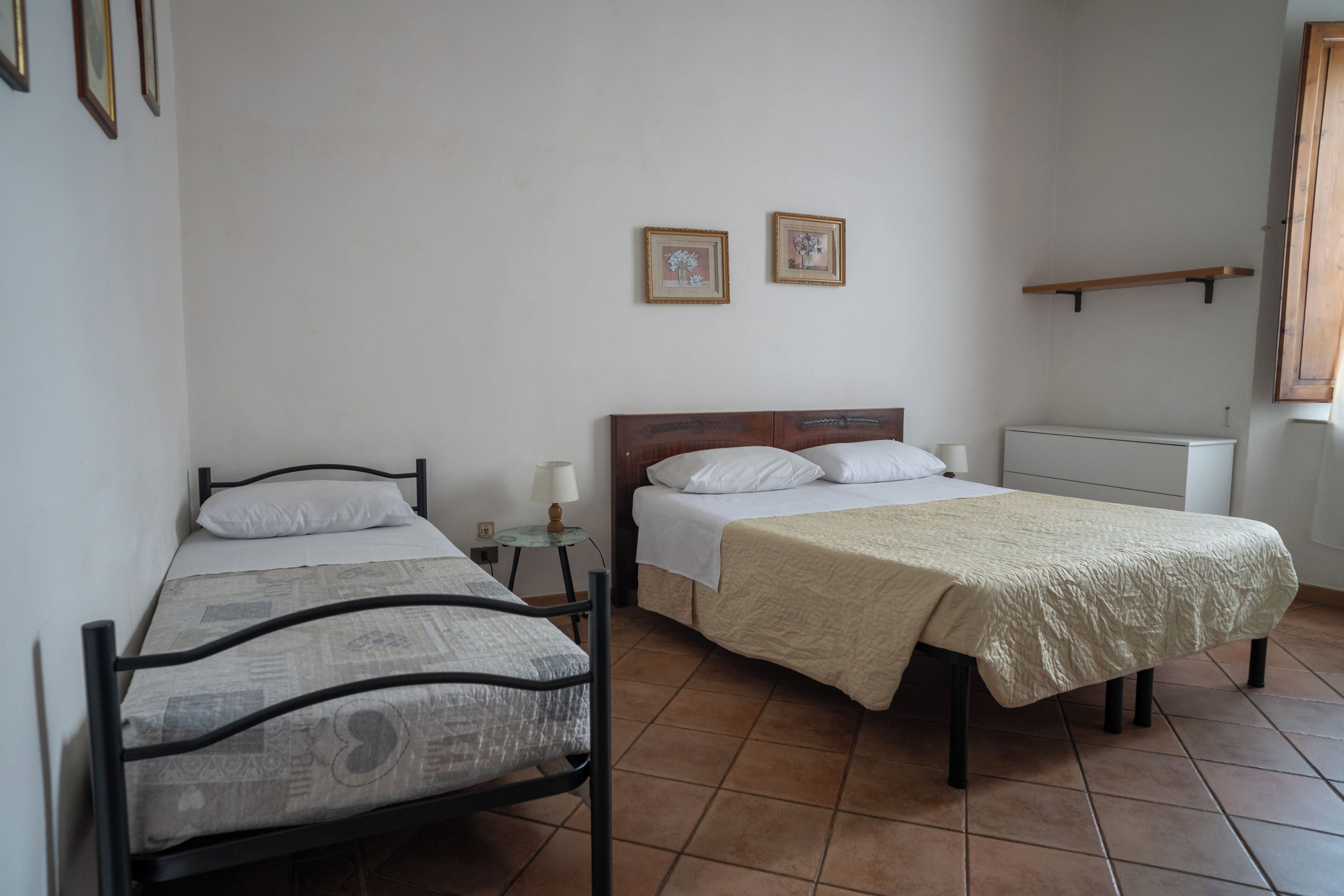 Een kamer met twee bedden, een klein tafeltje met een lamp en een radiator.