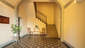 Ein Flur mit einem gemusterten Boden, einer Treppe und einer kleinen Sitzecke mit Stühlen und einem Tisch.