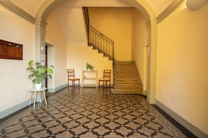 Ein Flur mit einem gemusterten Boden, einer Treppe und einer kleinen Sitzecke mit Stühlen und einem Tisch.