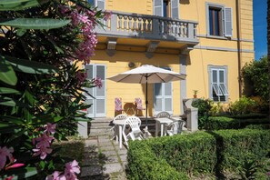 Ein gelbes Gebäude mit Balkon, Außenbereich und einer Hecke.