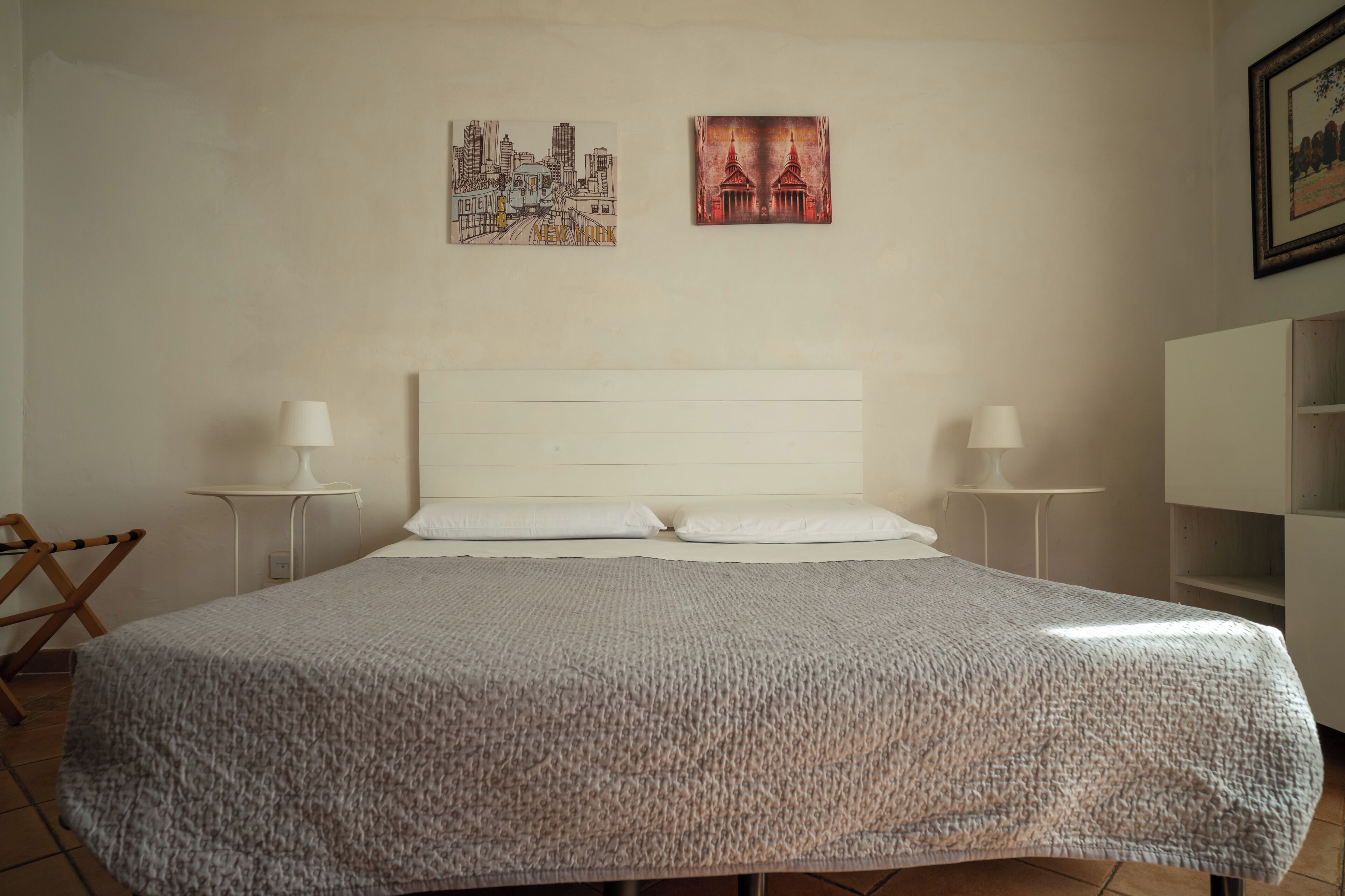 Een slaapkamer met een groot bed, twee nachtkastjes en twee wandlampen.
