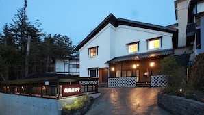 Un bâtiment à deux étages, avec une façade blanche et un toit foncé. On peut voir une enseigne avec des caractères japonais sur la devanture.