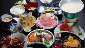 Verschiedene japanische Gerichte, darunter Sushi, Sashimi und Reisgerichte, präsentiert auf einem Tisch.