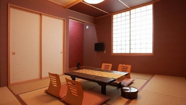 Une pièce de style japonais traditionnel, avec un sol recouvert de tatamis, une table basse et des portes coulissantes.