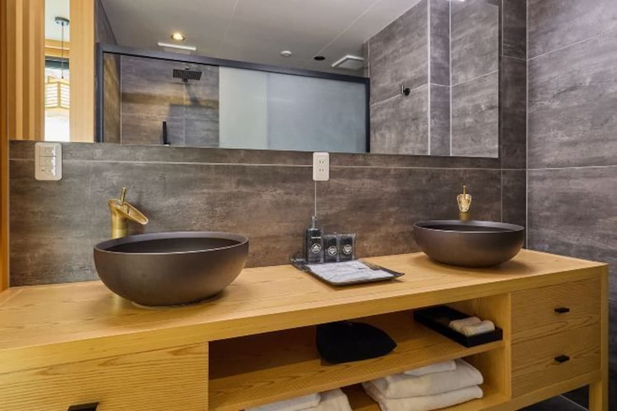 Un baño con dos lavamanos sobre encimera, un mueble de tocador de madera y un espejo grande.