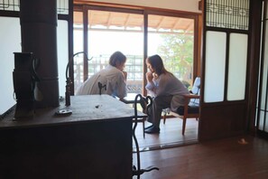 A traditional Japanese room with tatami flooring, a low table with a kettle, and sliding doors leading to a balcony. - Manai7.stay (Izumo)
