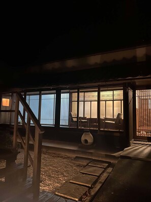 A building with multiple windows, a wooden staircase, and a seating area with chairs and a table. - Manai7.stay (Izumo)