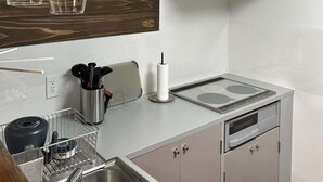 Una cocina moderna con un lavamanos de acero inoxidable, un horno empotrado y una campana extractora blanca.