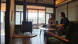 Un interior tradicional con suelo de tatami, una mesa baja y una silla acolchada verde.