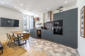 A modern kitchen with a dining area, built-in appliances, and a hexagonal patterned floor. - Modern Apartment a/c 2CH/4P - Cannes (Cannes)