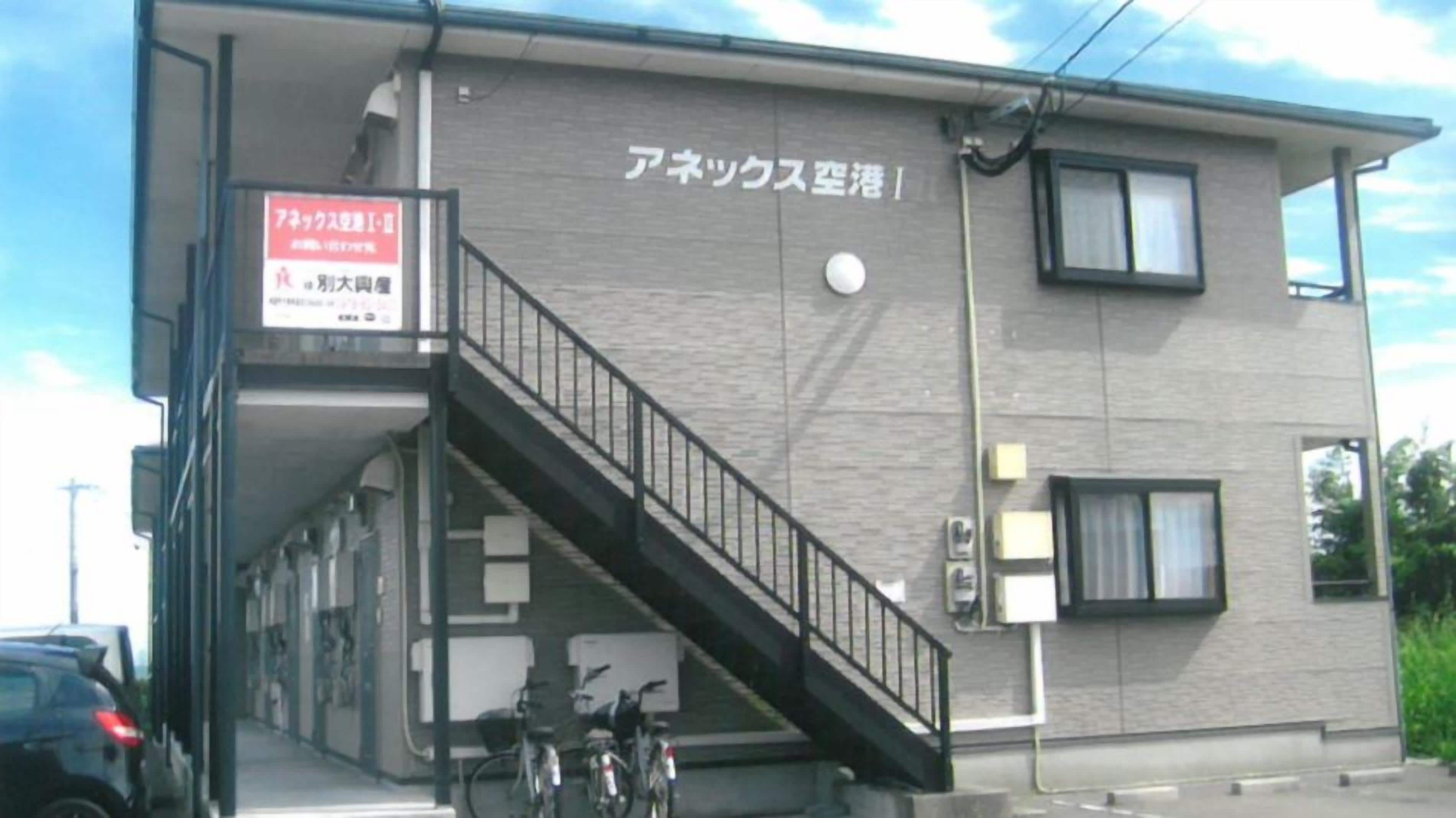 Un edificio con una escalera que lleva a la entrada, un letrero y una bicicleta estacionada afuera.