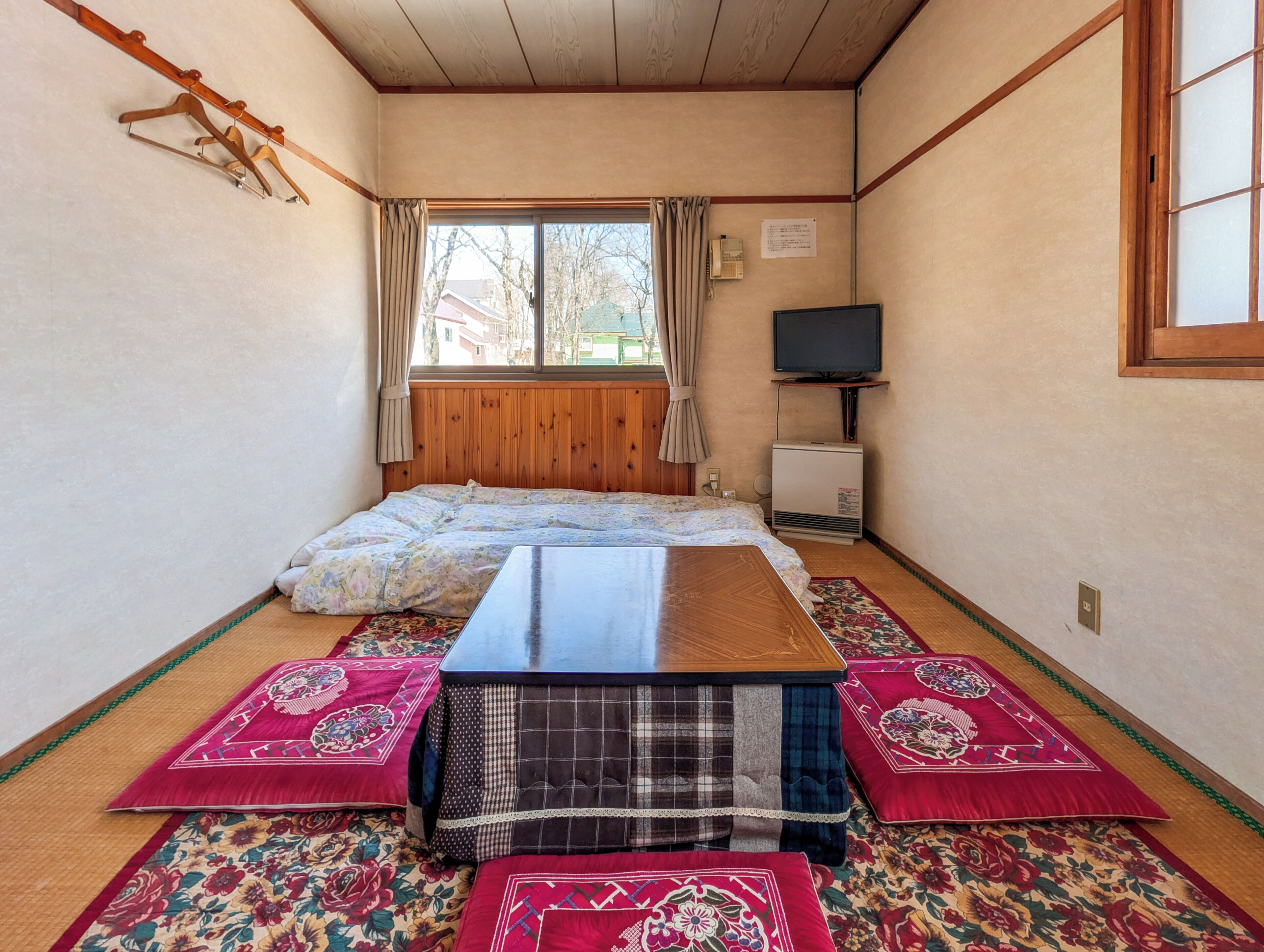 A room with a bed, a TV, and a wooden ceiling.