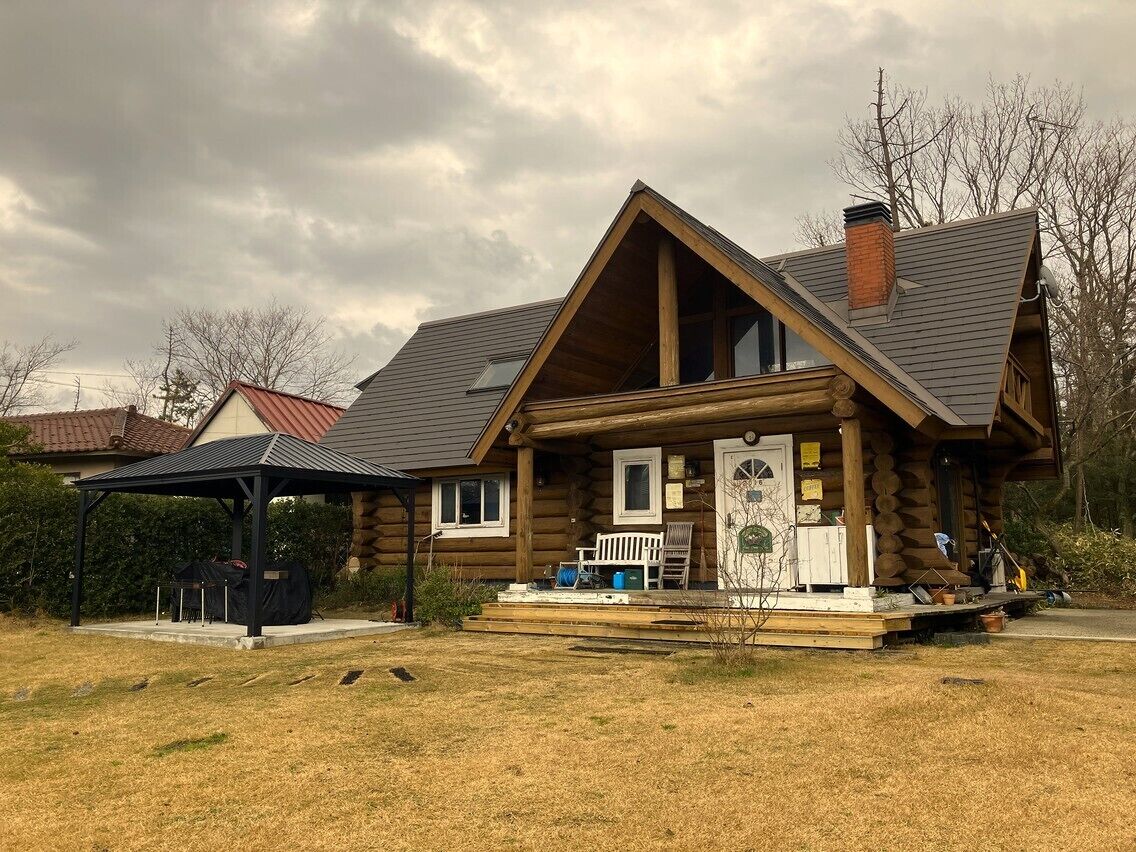 Une cabane en rondins avec une véranda, un patio couvert et une cheminée.