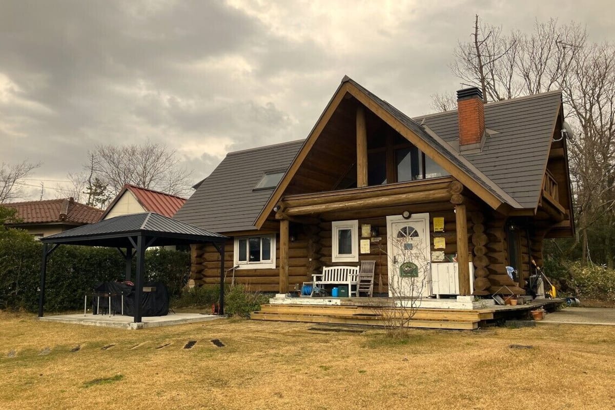Une cabane en rondins avec une véranda, un patio couvert et une cheminée.