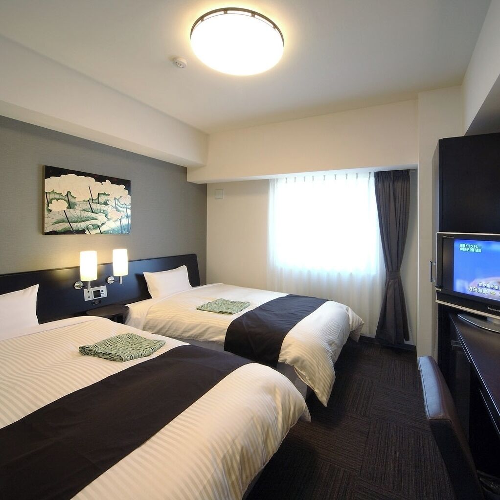 A hotel room with two beds, a flat-screen TV, a painting on the wall, and a window with curtains.