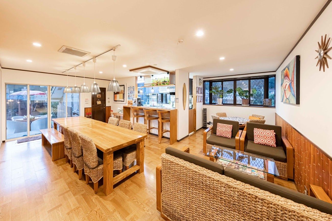 A spacious room with a wooden dining table, a sofa with cushions, and a large window offering a view.
