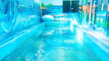 A pool area with clear water, a bench, and a wall with a mural.